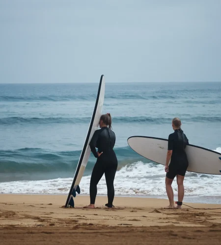 two-women-wetsuits-with-surfboards-are-getting-ready-go-into-water-cool-summer-day